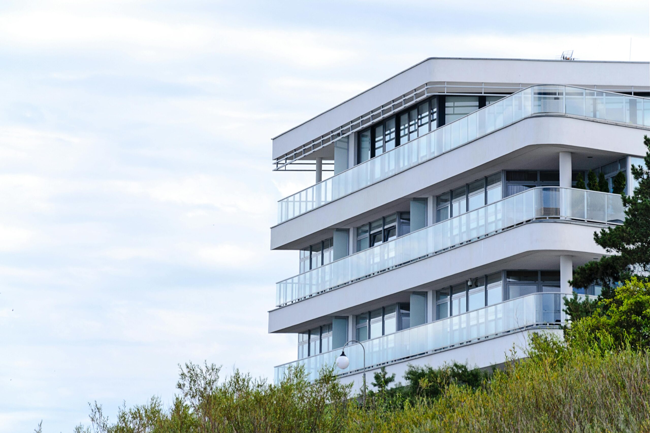 A contemporary apartment building with glass balconies and sleek design set against a clear sky.